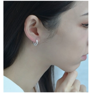 Close-up of S925 sterling silver triple-layered twisted hoop earrings worn by a model