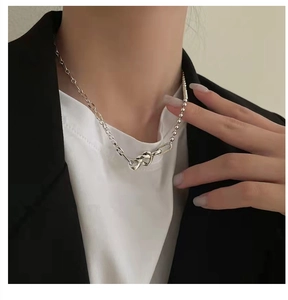 Gros plan d'un collier en argent S925 avec nœud en cœur porté sur un mannequin élégant
