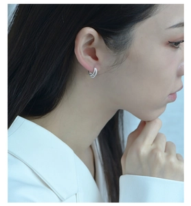 Close-up of S925 sterling silver twist hoop earrings with pavé texture on a model