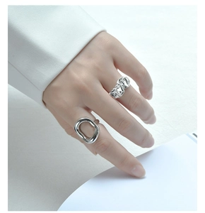 Detail shot of silver S925 rings with cutout pattern and crumpled texture on finger