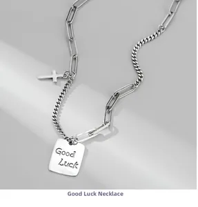 Close-up of S925 silver paperclip necklace featuring a Luck tag and cross pendant