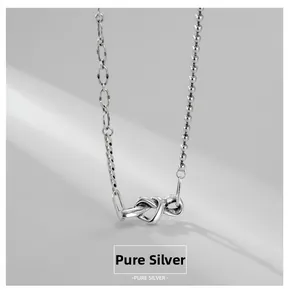 Vue détaillée du pendentif nœud en argent sterling S925 sur une chaîne asymétrique