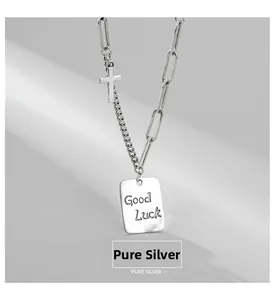 Macro detail of S925 sterling silver square Good Luck pendant and cross on mixed chain