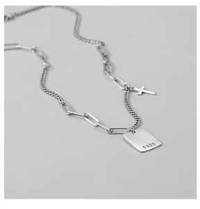 Detailed close-up of S925 sterling silver square pendant and cross on a paperclip chain