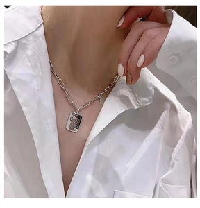 Close-up of S925 sterling silver LUCK square plate necklace and cross charm on model
