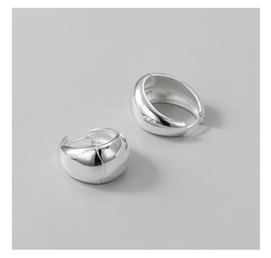 Macro shot of silver crescent earrings with a polished surface and thick minimalist design
