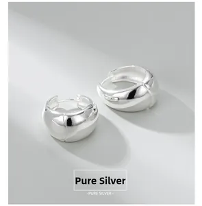 Macro detail of polished sterling silver hoop earrings with high-gloss finish