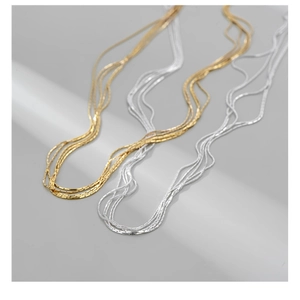 Macro detail of minimalist multi-layered gold and silver layered necklace chains