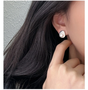 Close-up of S925 silver stud earring with white pearl on model's ear in natural light