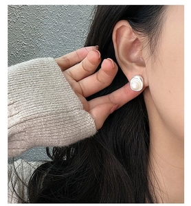 Close-up of S925 sterling silver pearl earring with irregular metal frame on model