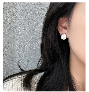 Detailed view of an irregular silver stud earring with a polished white round pearl