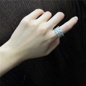 S925 sterling silver pleated ring with twist chain design on a dark wood background