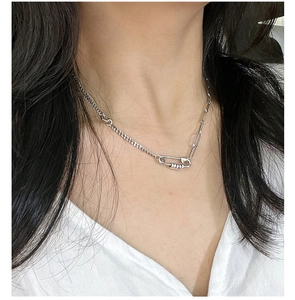 Detail of S925 silver paperclip necklace showing asymmetrical chain and safety pin charm