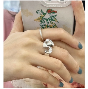 Close-up of a S925 sterling silver abstract curved ring worn on finger in daily setting