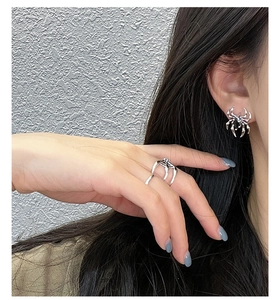 Detailed close-up of dark gothic spider earring and ring set in polished silver finish