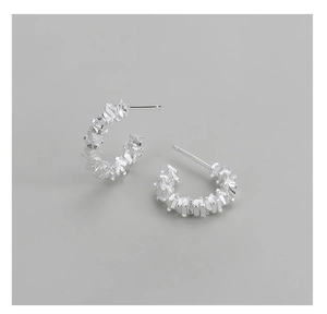 Detailed macro shot of S925 sterling silver C-shaped earrings with crushed silver texture