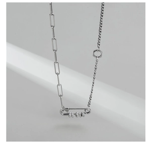 Detail of S925 silver paperclip chain necklace with industrial pin pendant and hexagon nut