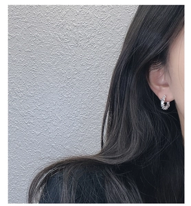 Close-up of S925 sterling silver hoop earring with irregular textured surface on model