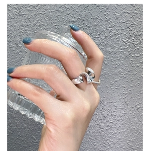 Close-up of S925 sterling silver irregular ribbon ring worn by a model with blue nails