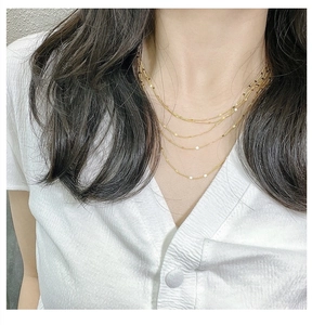 Détail d'un collier multicouche en argent S925 doré avec des paillettes métalliques