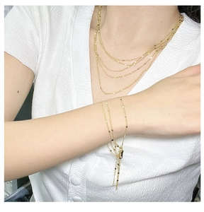 Gros plan d'un collier multicouche doré élégant et d'un bracelet assorti sur un mannequin