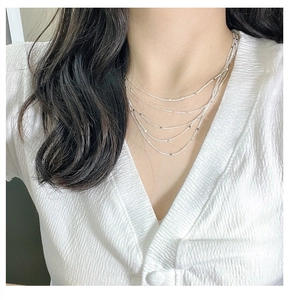 Gros plan d'un collier multicouche en argent sterling S925 avec fines chaînes sur un mannequin