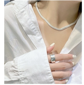 Detail of silver S925 flat snake bone chain necklace and wide embossed texture ring