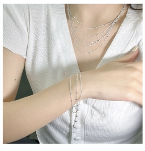 Détail de colliers et bracelet multicouches en argent S925 avec breloques disques plats