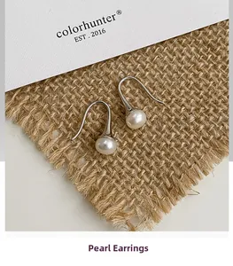 Détail de boucles d'oreilles perles d'eau douce sur lin avec carte pour un style élégant