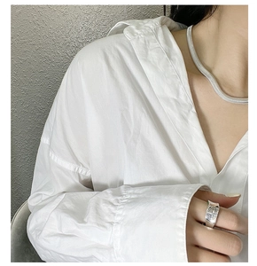 Detail of wide silver ring with embossed saturn logo worn with a sleek snake chain