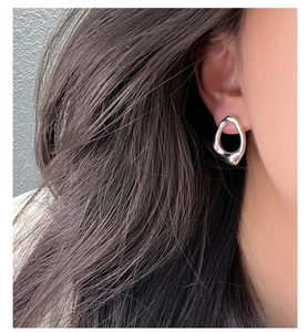 Dettaglio dell'orecchino in argento irregolare con texture in metallo liquido su modella