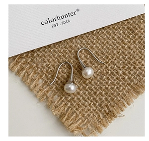 Détail de boucles d'oreilles crochet en argent S925 avec perles d'eau douce sur fond rétro