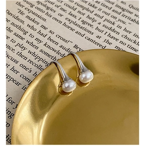 Gros plan sur les boucles d'oreilles pendantes en argent S925 et or avec perles d'eau douce blanches
