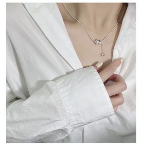 Macro detail of s925 silver snake chain necklace featuring a polished bead and vertical pendant