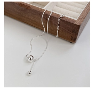 Detailed macro view of S925 sterling silver snake chain with minimalist double bead pendant