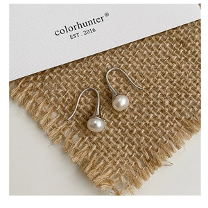 Détail de boucles d'oreilles crochet en argent S925 avec perles d'eau douce sur tissu texturé