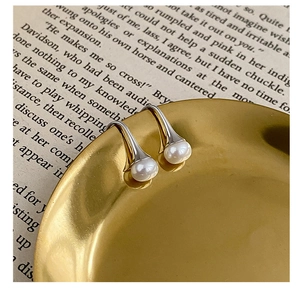 Détail de boucles d'oreilles perles vintage sur un plateau doré sur des pages de livre