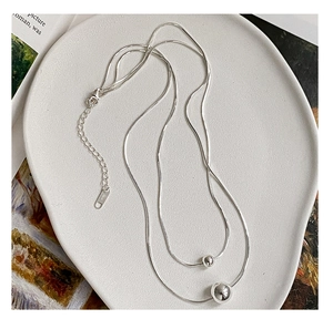 Detail of double-layer S925 sterling silver snake chain with polished round bead pendants