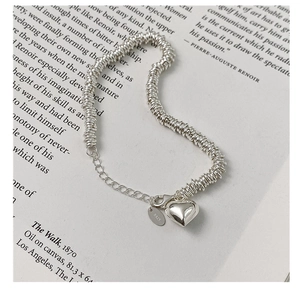 Macro view of S925 sterling silver heart bracelet with threaded rings on a book