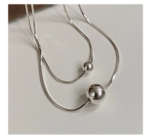 Detailed close-up of S925 sterling silver layered snake chain with polished bead pendants