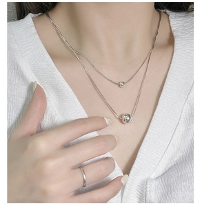 Detail of minimalist double-layered S925 silver necklace with two polished spherical beads