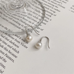 Boucles d'oreilles élégantes en argent S925 et perles d'eau douce sur une page de livre