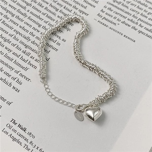 Elegant S925 sterling silver heart bracelet with a textured link chain on a white book