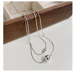 Close-up of double layer silver snake chain necklace with polished bead pendants