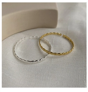 Detail of minimalist S925 sterling silver twisted open bracelets in gold and silver