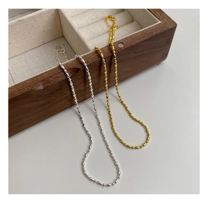 Détail de colliers de perles de riz en argent et or avec fermoir mousqueton sur boîte
