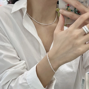 Sparkling 925 sterling silver twist chain necklace and bracelet set on a white shirt