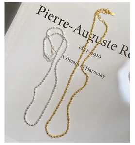 Détail de colliers à billes en argent et or avec fermoir mousqueton sur un livre