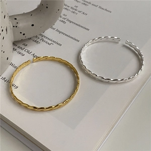 Minimalist twisted wire open bracelets in gold and silver finish set on an art book