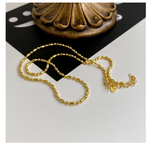 Détail macro du collier en argent S925 doré avec perles olive et rondes élégantes